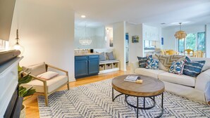 A modern living room with a sofa, coffee table, and a kitchen area in the background. - Kiawah Island Vacation Rental: Walk to Beach! (Kiawah Island)