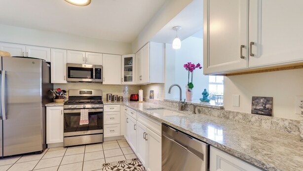 A modern kitchen with stainless steel appliances, white cabinetry, and a marble countertop. - Bradenton Retreat Near Beaches w/ BBQ & Fire Pit (Bradenton)