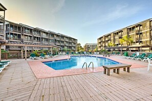 A pool area with a wooden deck, lounge chairs, and a swimming pool. - Walk to Coast: North Myrtle Beach Condo w/ Pool! (North Myrtle Beach)