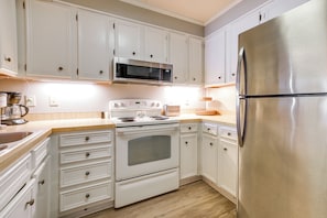 A kitchen with white cabinets, a stainless steel refrigerator, a microwave, and a stove. - Walk to Coast: North Myrtle Beach Condo w/ Pool! (North Myrtle Beach)