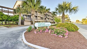 A sign for the Tilghman Beach & Racquet Club, surrounded by landscaped areas with palm trees and flowering shrubs. - Walk to Coast: North Myrtle Beach Condo w/ Pool! (North Myrtle Beach)