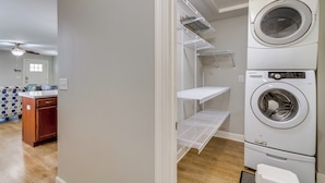 Una lavanderia con lavatrici e asciugatrici affiancate, mobili impiallacciati in legno e una ventola a soffitto.