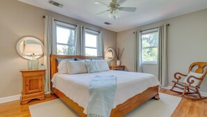 Ein Schlafzimmer mit einem großen Bett, zwei Nachttischen, einem Schaukelstuhl und einem Deckenventilator.