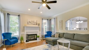 A living room with a fireplace, blue armchairs, a grey sofa, and a ceiling fan. - Lakefront Raleigh Retreat ~ 7 Mi to Downtown! (Raleigh)