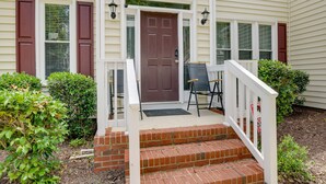 A two-story house with a front porch, a brown door, and a small set of steps leading up to the entrance. - Lakefront Raleigh Retreat ~ 7 Mi to Downtown! (Raleigh)