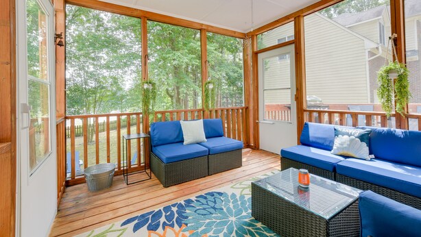 A covered porch with a blue sofa, a glass table, and a metal bucket. - Lakefront Raleigh Retreat ~ 7 Mi to Downtown! (Raleigh)