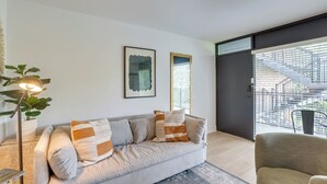 Ett modernt vardagsrum med en grå soffa, ett litet bord och en krukväxt.