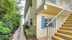 A building with a concrete pathway, a staircase with yellow steps, and a balcony with blue shutters. - Longboat Key Vacation Rental: Direct Beach Access! (Longboat Key)