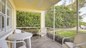 A covered patio with white wicker furniture, a ceiling fan, and a view of greenery. - Longboat Key Vacation Rental: Direct Beach Access! (Longboat Key)