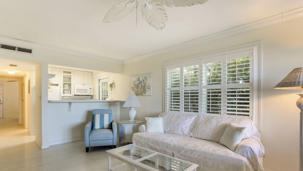 A living room with a sofa, coffee table, and a lamp. There is a chair and a side table with a lamp. A window with blinds is visible. - Longboat Key Vacation Rental: Direct Beach Access! (Longboat Key)