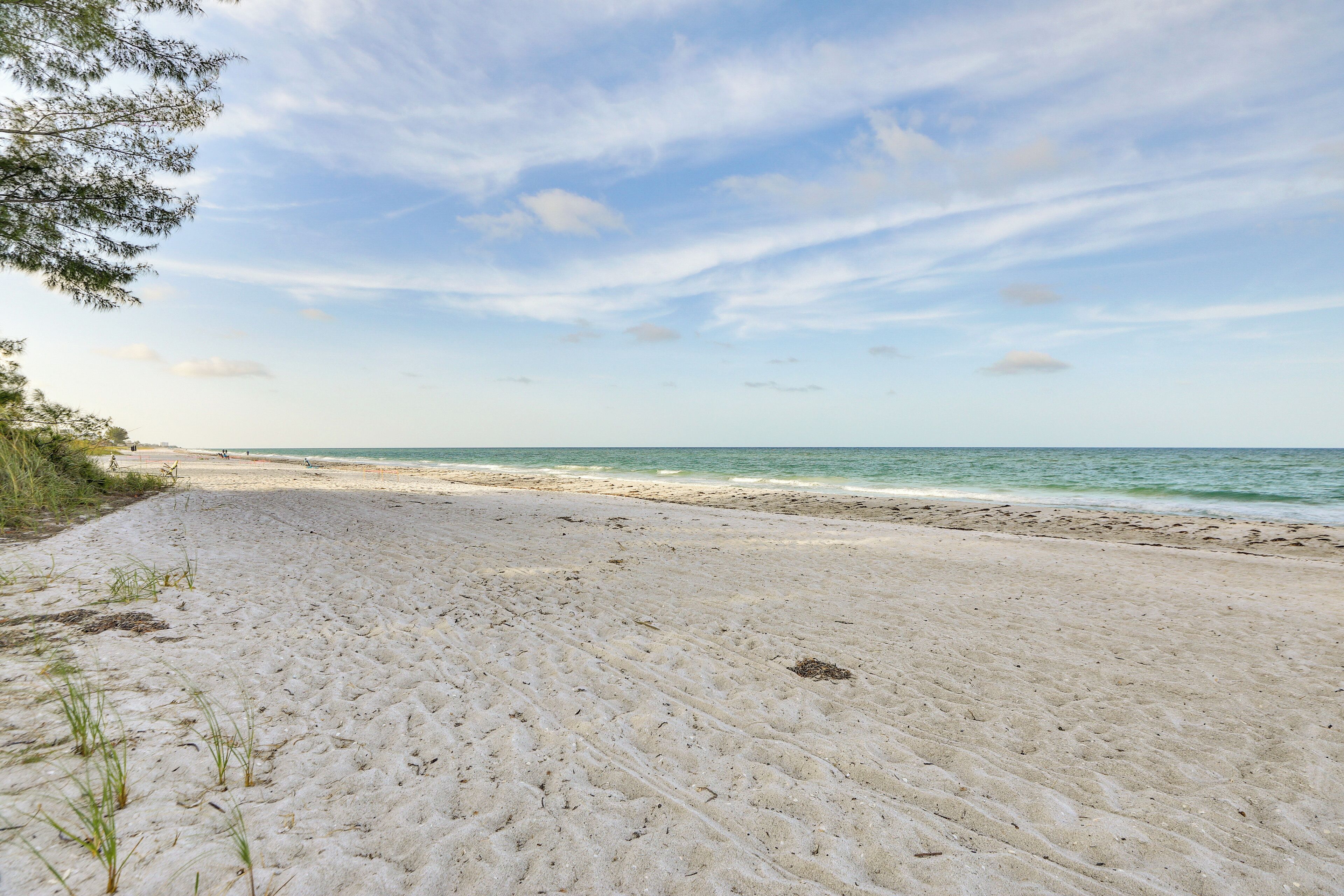 A sandy beach with a clear sky and calm sea.