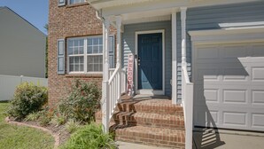 A two-story house with a front porch, a blue door, and a garage. - Raleigh Home w/ Modern Adjustable Sleeping System (Raleigh)