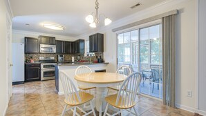A kitchen with dark cabinets, a microwave, oven, and a dining area with a round table and four chairs. - Raleigh Home w/ Modern Adjustable Sleeping System (Raleigh)