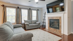 A living room with a grey sofa, a fireplace, and a flat-screen TV mounted above it. - Raleigh Home w/ Modern Adjustable Sleeping System (Raleigh)