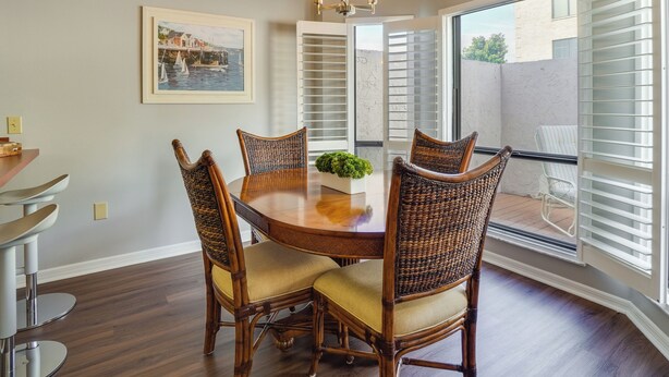A dining area with a round wooden table, four wicker chairs, and a chandelier. - Walk to Restaurants: Downtown Leesburg Townhome! (Leesburg)