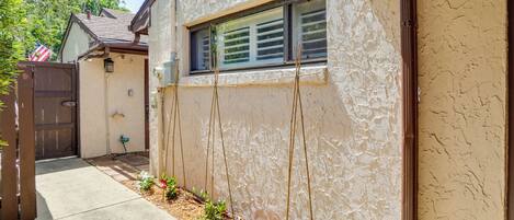 Uma casa residencial com um caminho de concreto, cerca de madeira e uma janela com persianas.