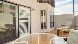 A glass table with chairs on a wooden deck, a sliding glass door, and a small balcony with a chair. - Walk to Restaurants: Downtown Leesburg Townhome! (Leesburg)