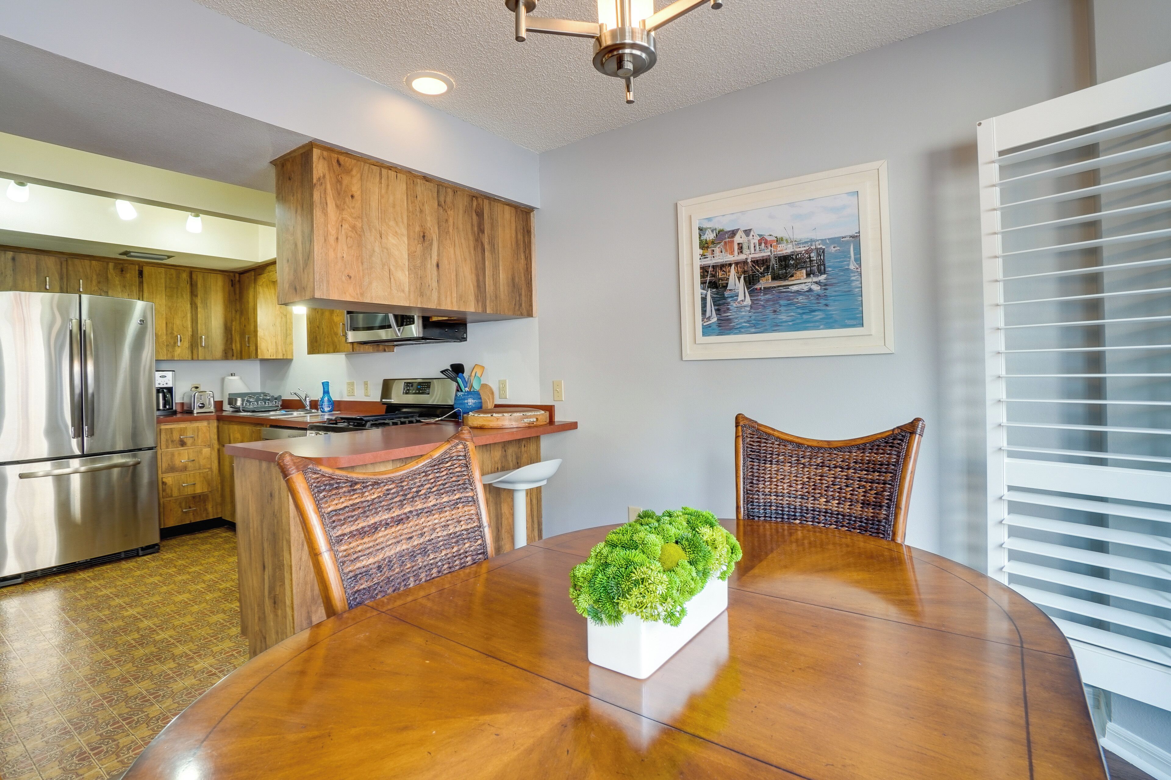 Una cocina moderna con armarios de madera, electrodomésticos de acero inoxidable y un comedor con mesa y sillas de madera.
