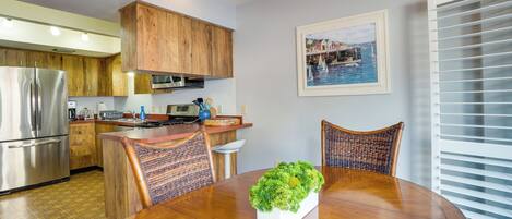 Una cocina moderna con armarios de madera, electrodomésticos de acero inoxidable y un comedor con mesa y sillas de madera.