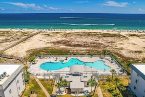 A resort with a large pool area, a beach with umbrellas, and a view of the ocean. - Walk to Beach! Gulf Shores Escape w/ Indoor Pool (Gulf Shores)