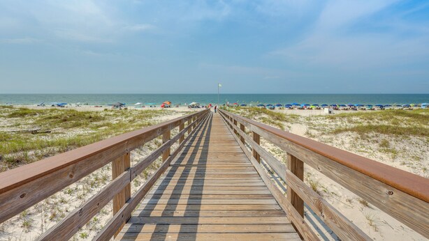 A wooden boardwalk leading to a beach with umbrellas and beach chairs. - Walk to Beach! Gulf Shores Escape w/ Indoor Pool (Gulf Shores)