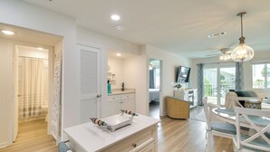 A modern living room with a dining area, a kitchen, and a bathroom. - Walk to Beach! Gulf Shores Escape w/ Indoor Pool (Gulf Shores)