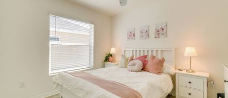 A bedroom with a bed, nightstands, a ceiling fan, and artwork on the wall.