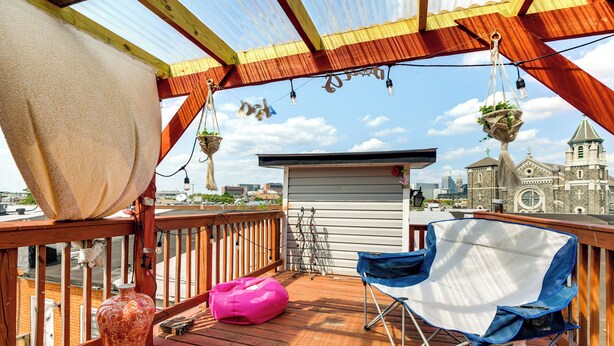 A wooden deck with a blue folding chair, a pink bean bag, and a hanging plant. - Quirky Baltimore Townhome ~ 2 Mi to Inner Harbor (Baltimore)