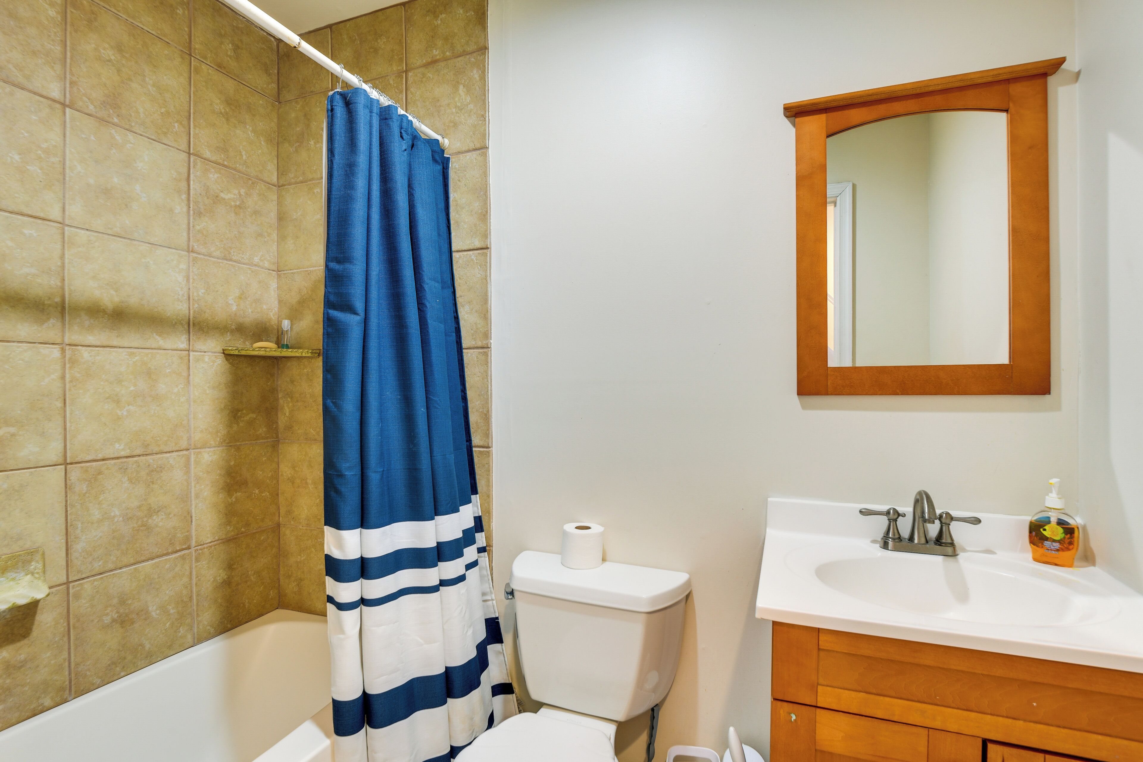 A bathroom with a bathtub, a toilet, a sink, and a mirror.