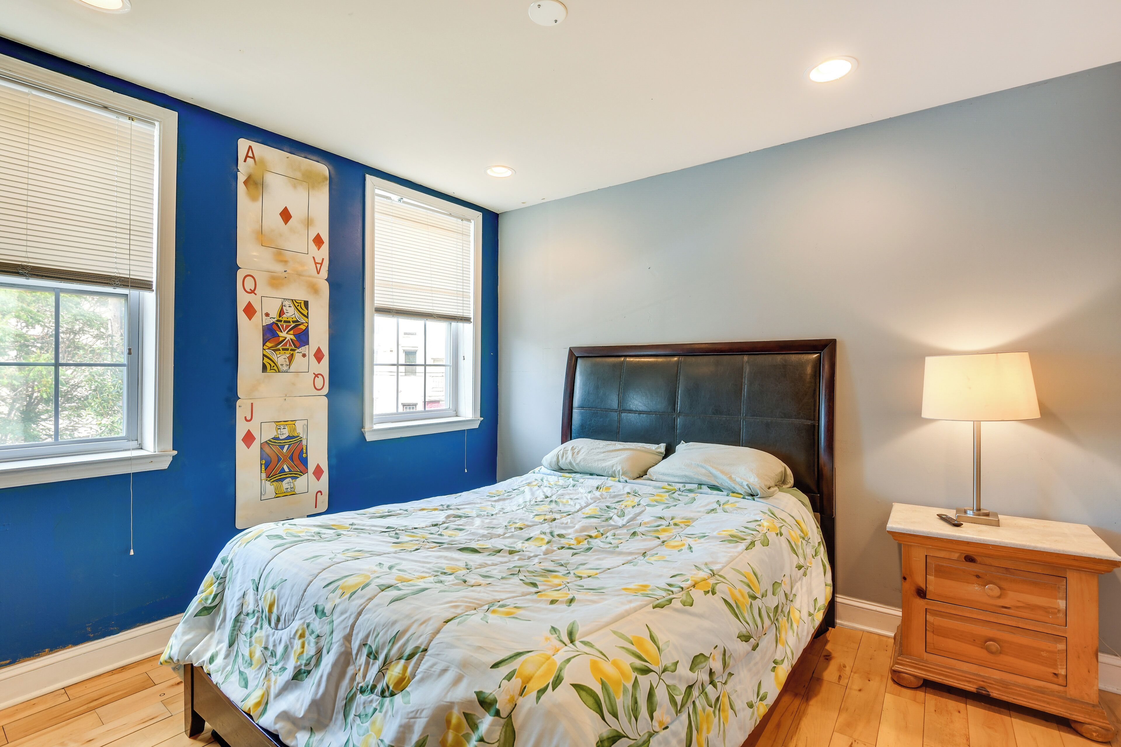 A bedroom with a bed, a nightstand, a lamp, and a window with blinds.