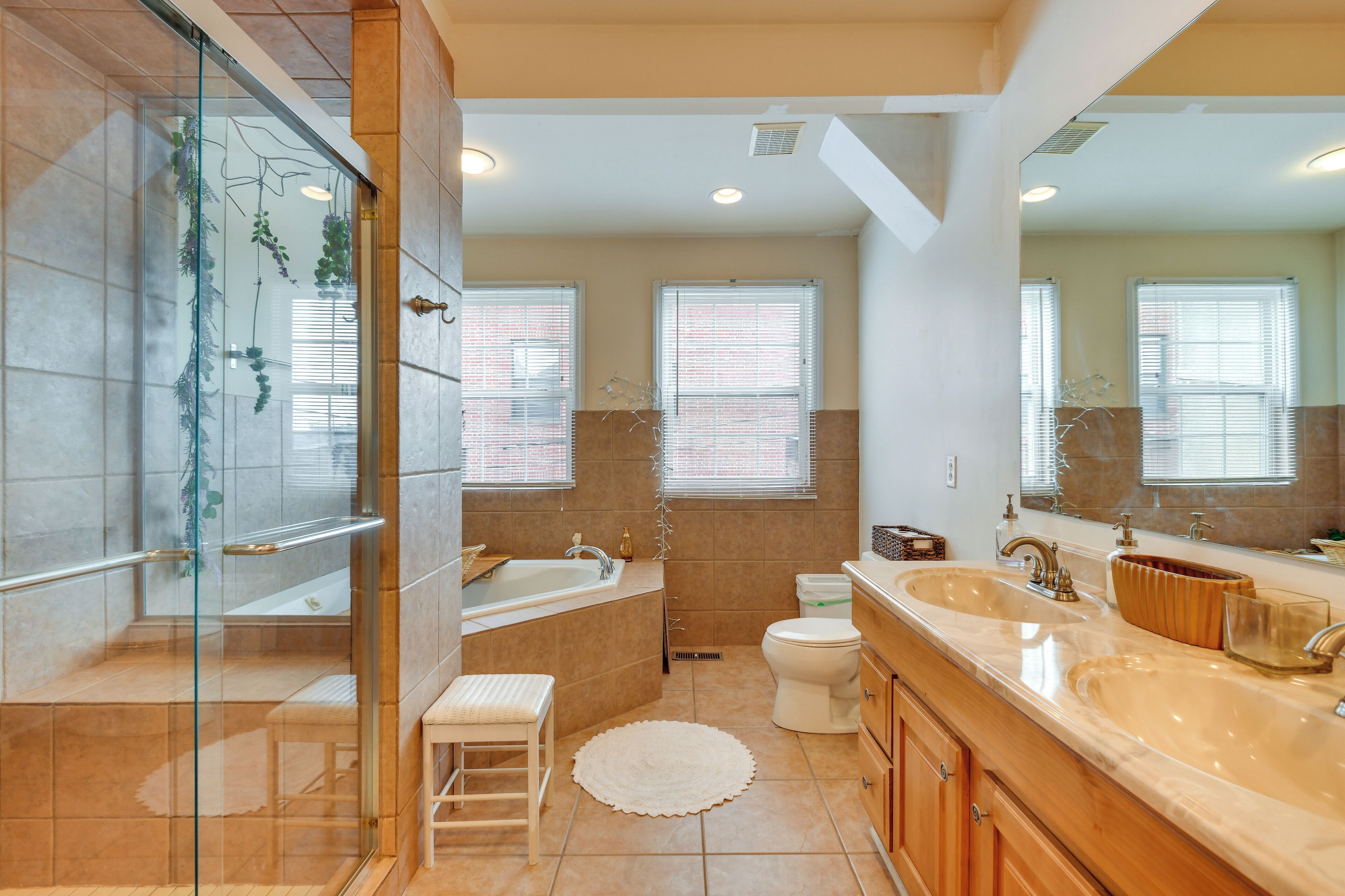Une salle de bain moderne dotée d’une douche à parois de verre, d’une baignoire sur pieds, de toilettes et d’un grand meuble-lavabo avec deux vasques.