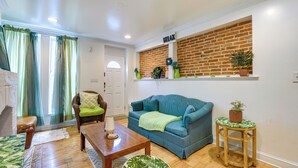 A living room with a blue sofa, wooden coffee table, and a wicker side table with a plant. - Quirky Baltimore Townhome ~ 2 Mi to Inner Harbor (Baltimore)