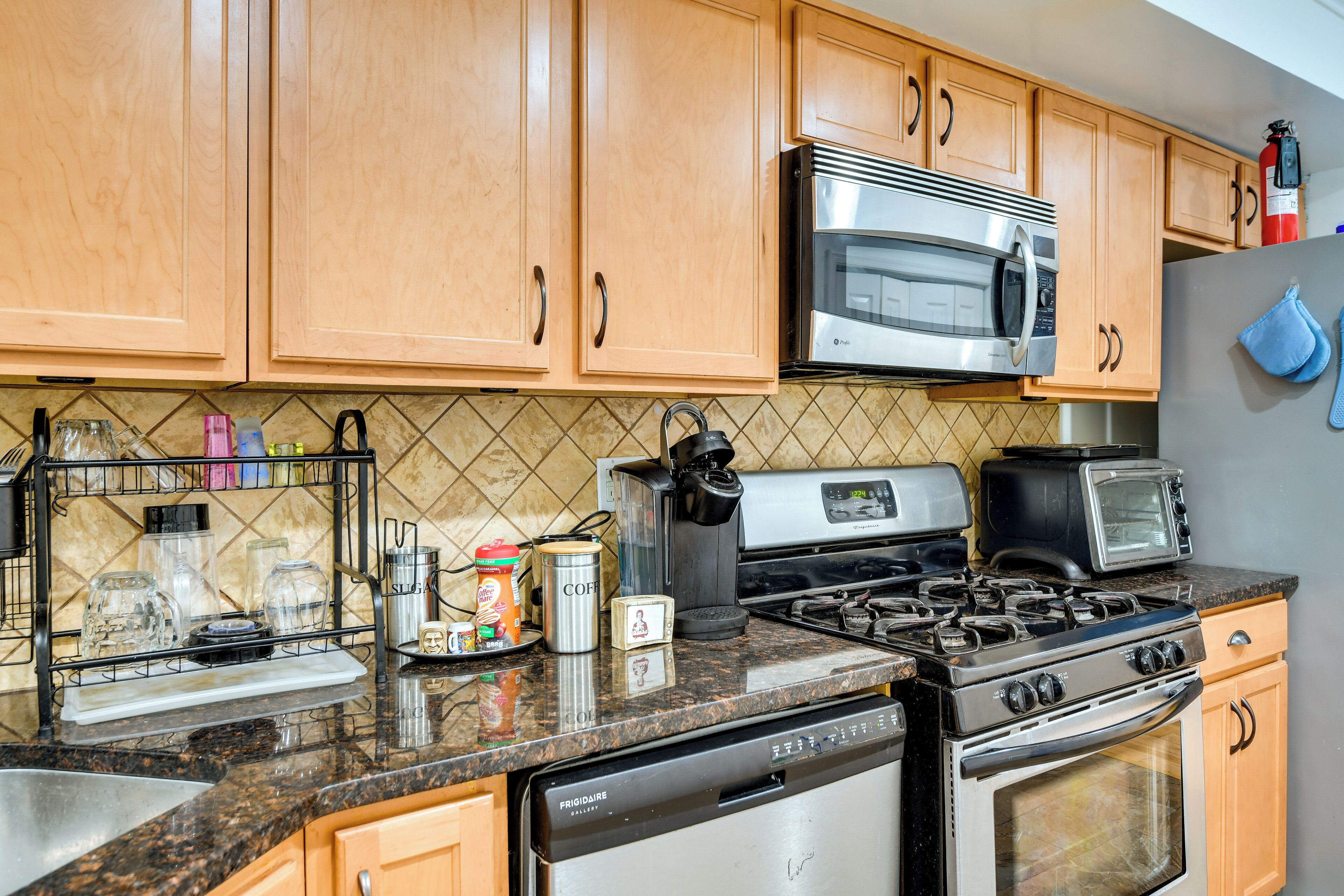 A kitchen with wooden cabinets, a stainless steel microwave, a gas stove, a dishwasher, and a toaster.