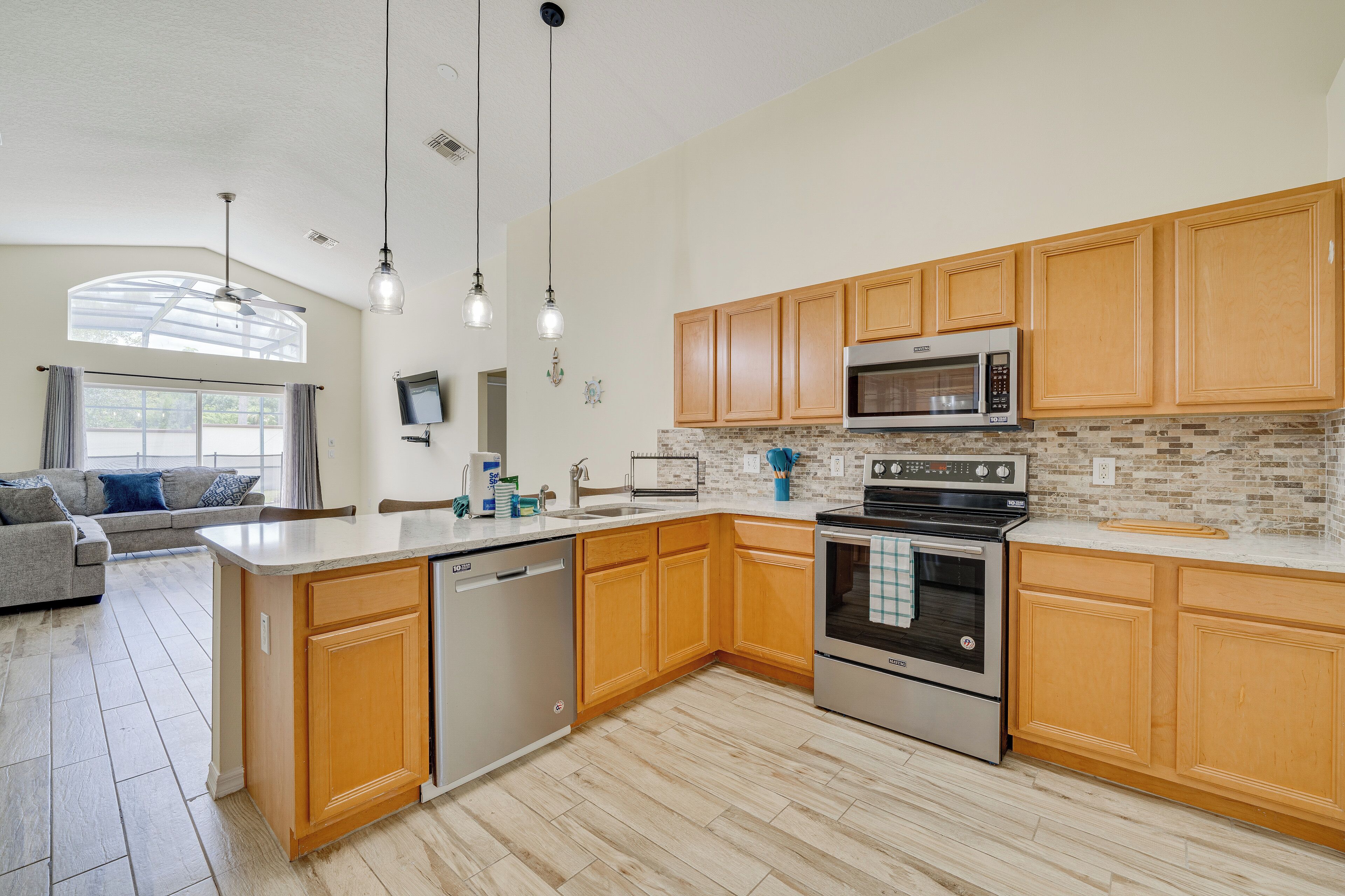 A modern kitchen with wooden cabinets, stainless steel appliances, and a large island.