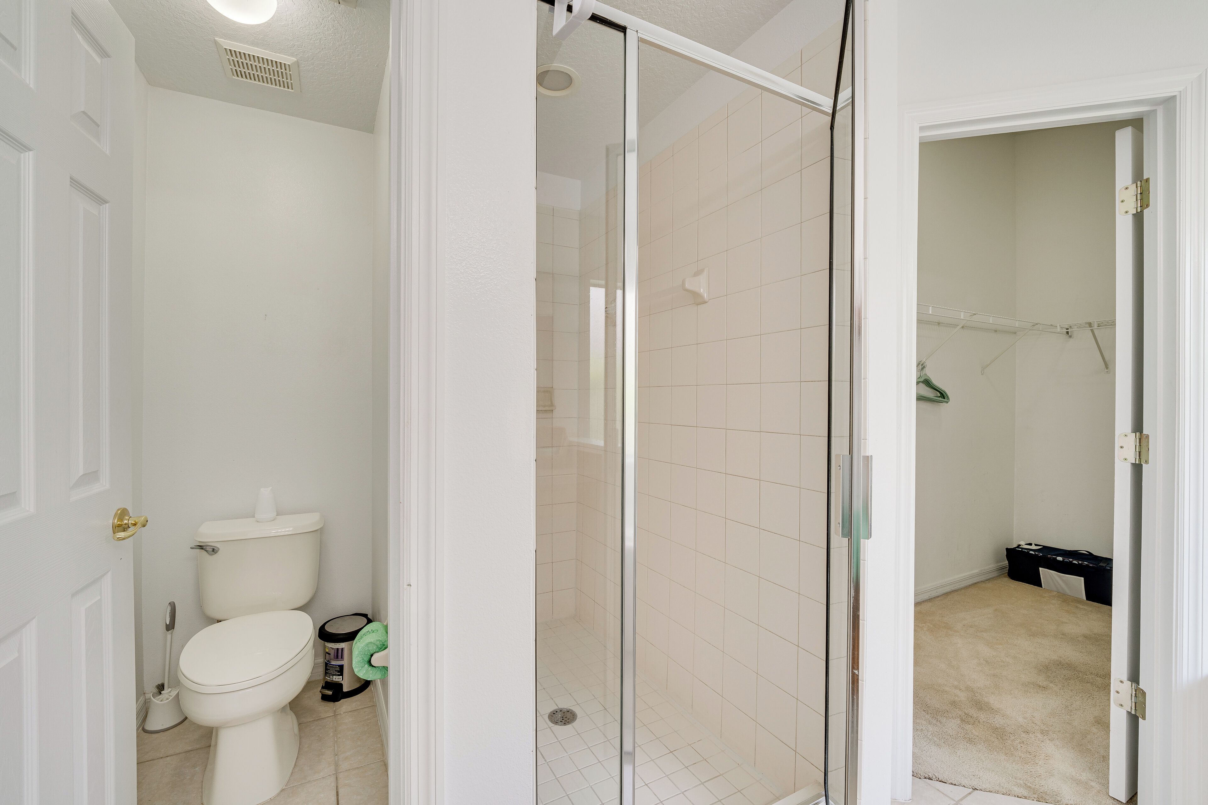 A bathroom with a toilet, a shower, and a walk-in closet.