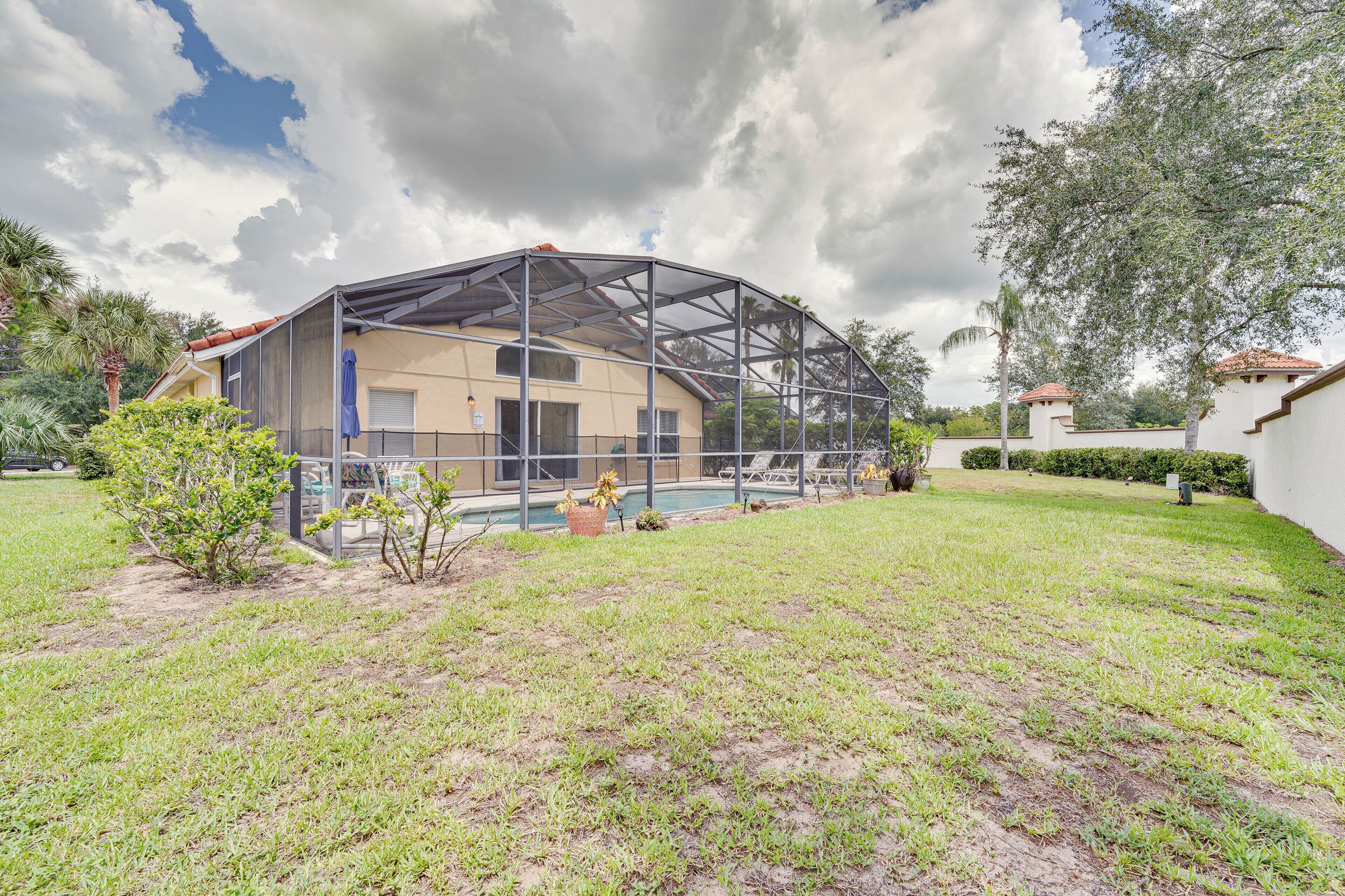 A house with a covered outdoor area, a swimming pool, and a lawn.