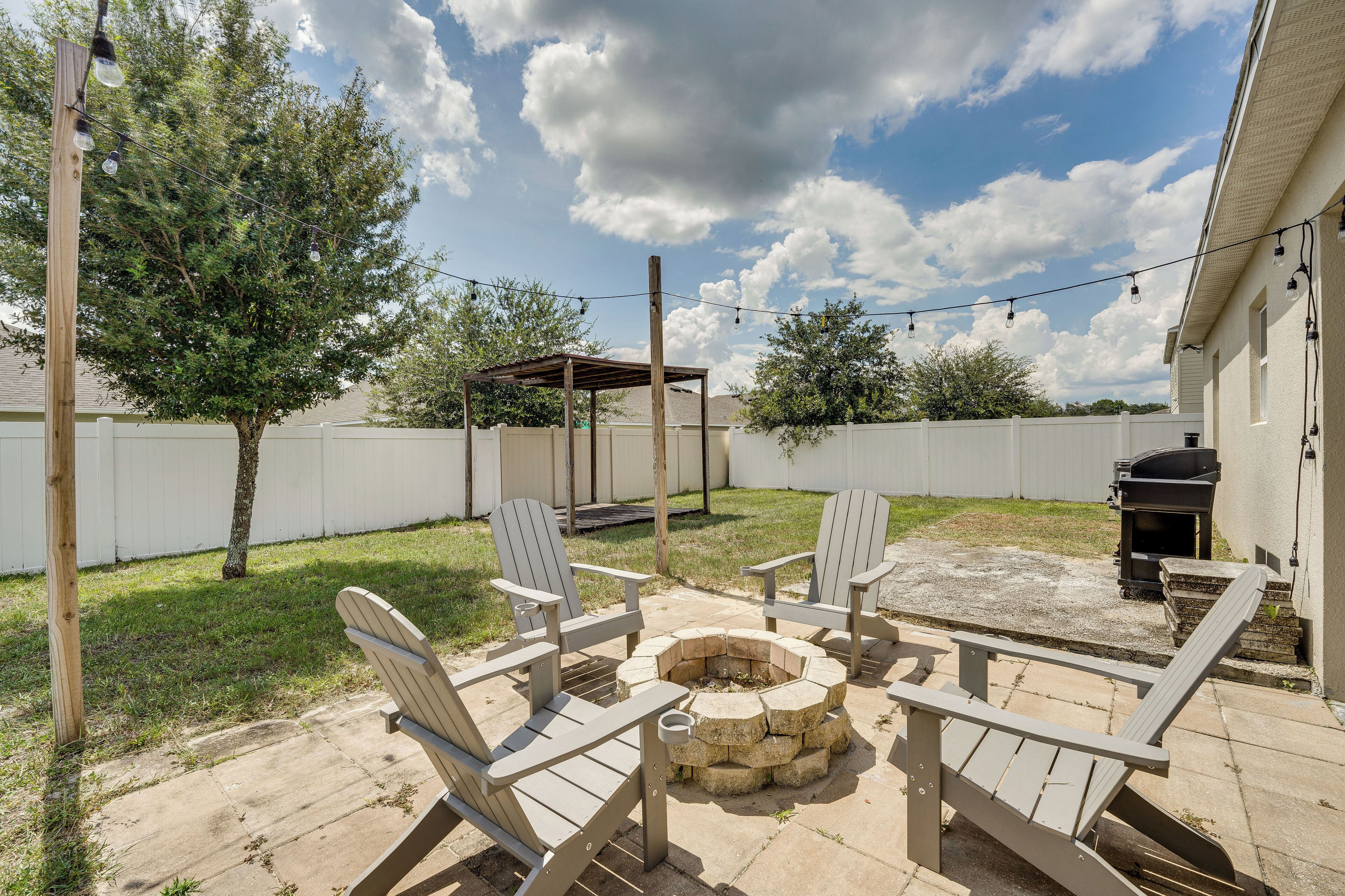 Une terrasse extérieure avec des fauteuils Adirondack, un foyer en pierre et un barbecue.