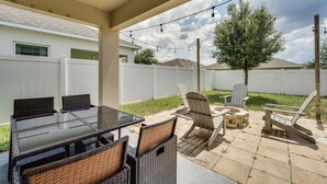 An outdoor patio with a glass-top table, wicker chairs, and Adirondack chairs.