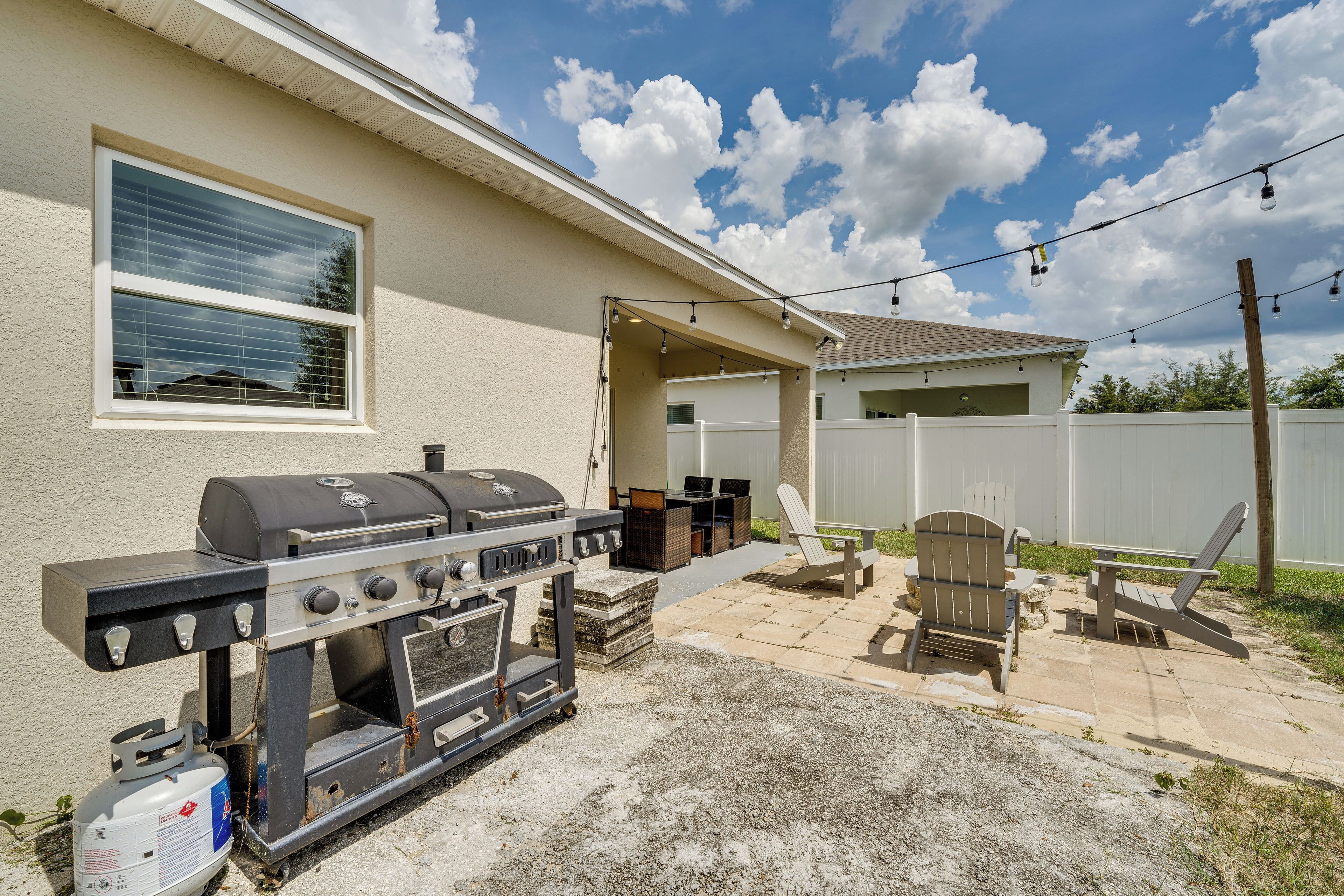 An outdoor patio with a barbecue grill, seating area, and a covered section.