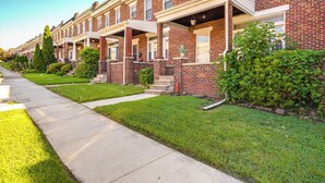 A row of brick townhouses with front porches, a sidewalk, and well-maintained lawns. - Baltimore Vacation Rental - Near JHU & Art Museum! (Baltimore)