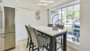Eine moderne Küche mit Marmorarbeitsplatte, einem Edelstahlkühlschrank und einem Essbereich mit Tisch und Stühlen.