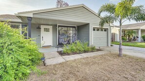 Ein modernes Einfamilienhaus mit überdachter Veranda, Garage und gepflegtem Rasen.