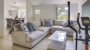 Ein modernes Wohnzimmer mit einem beigefarbenen Moduls Sofa, einem weißen Couchtisch und einem Laufband.