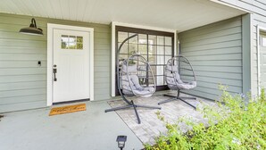 Eine Veranda mit einer weißen Tür, zwei Hängestühlen und einer kleinen Außenleuchte.