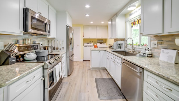 A modern kitchen with white cabinets, stainless steel appliances, and a granite countertop.