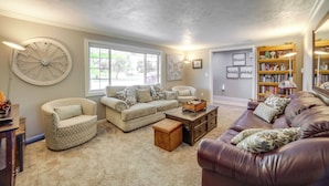 A living room with a beige sofa, a brown leather couch, a patterned armchair, and a wooden coffee table.