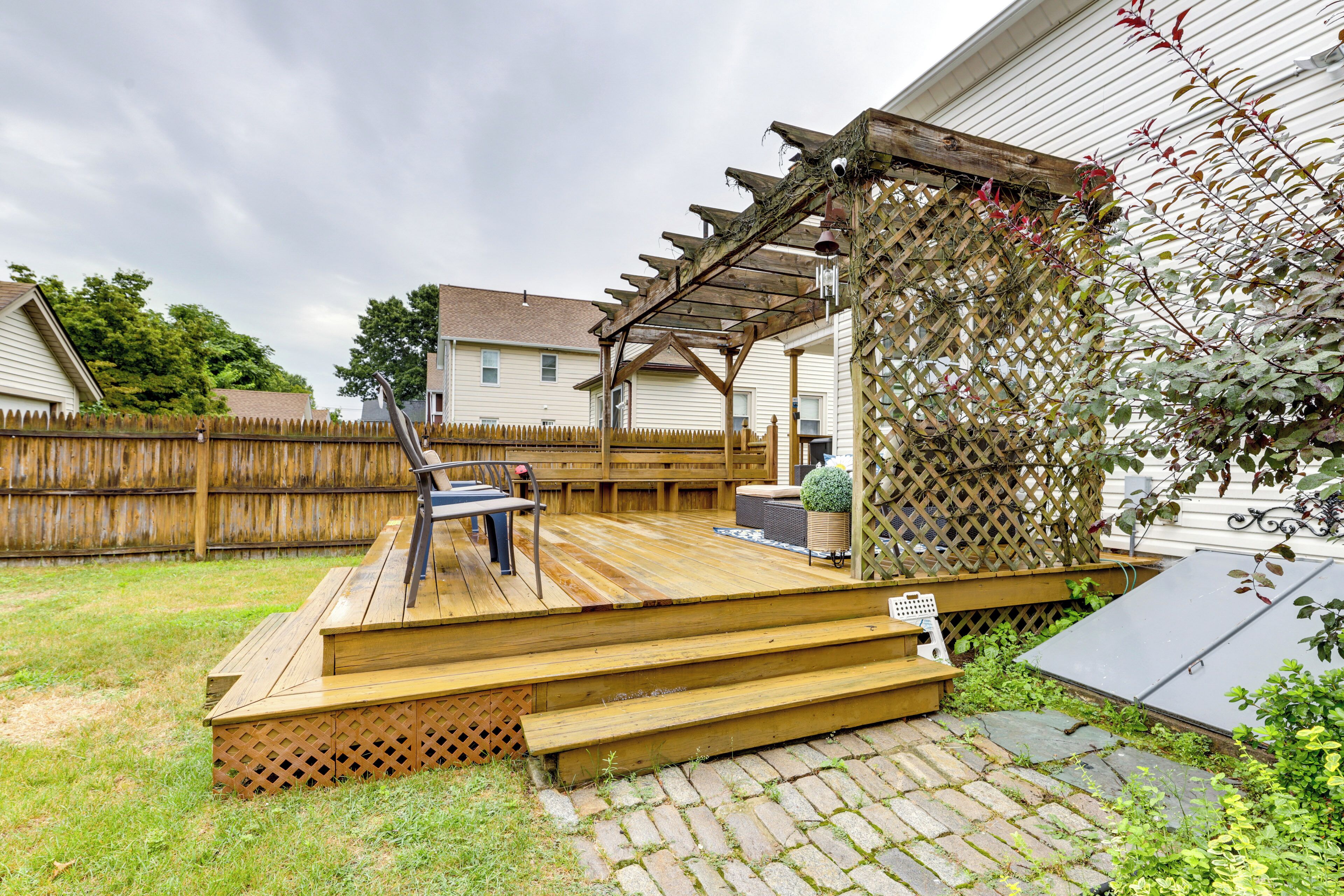 A wooden deck with a pergola, a patio table, and a potted plant.
