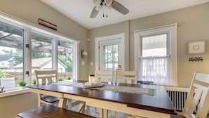 A dining area with a wooden table, white chairs, and a ceiling fan.
