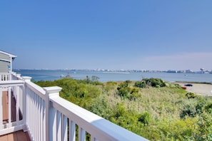 A balcony with a view of the sea and distant cityscape.