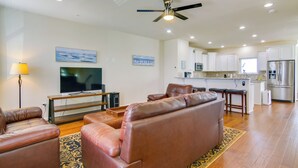 A modern living room with a brown leather sofa, a flat-screen TV, and a ceiling fan.